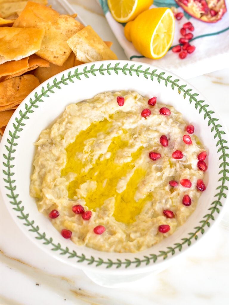 Lebanese Baba Gannouj in a bowl with green trim and red pomegranate seeds on top