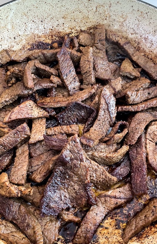 Beef strips in a saute pan for shawarma