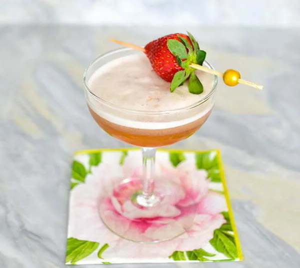 Strawberry cocktail with jam and gin in a coupe with a strawberry pick
