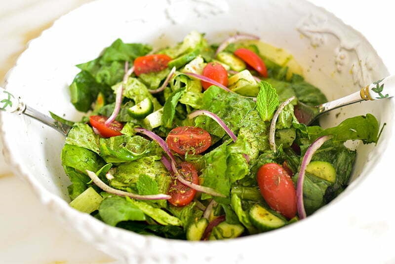 Lebanese salad being tossed in a white bowl