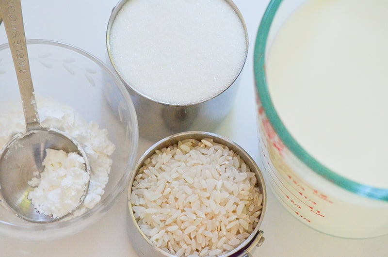 Ingredients for rice pudding in measuring cups, rice and sugar and milk