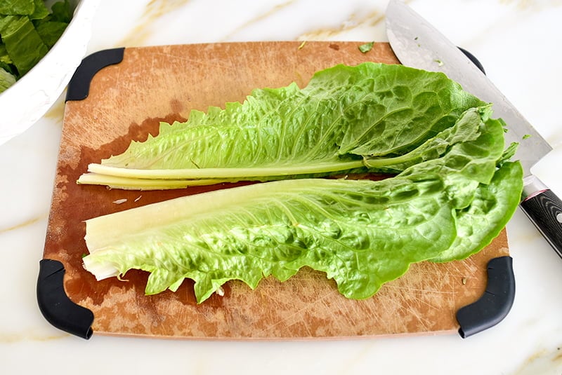 Romaine lettuce cut down the length of the rib on a board