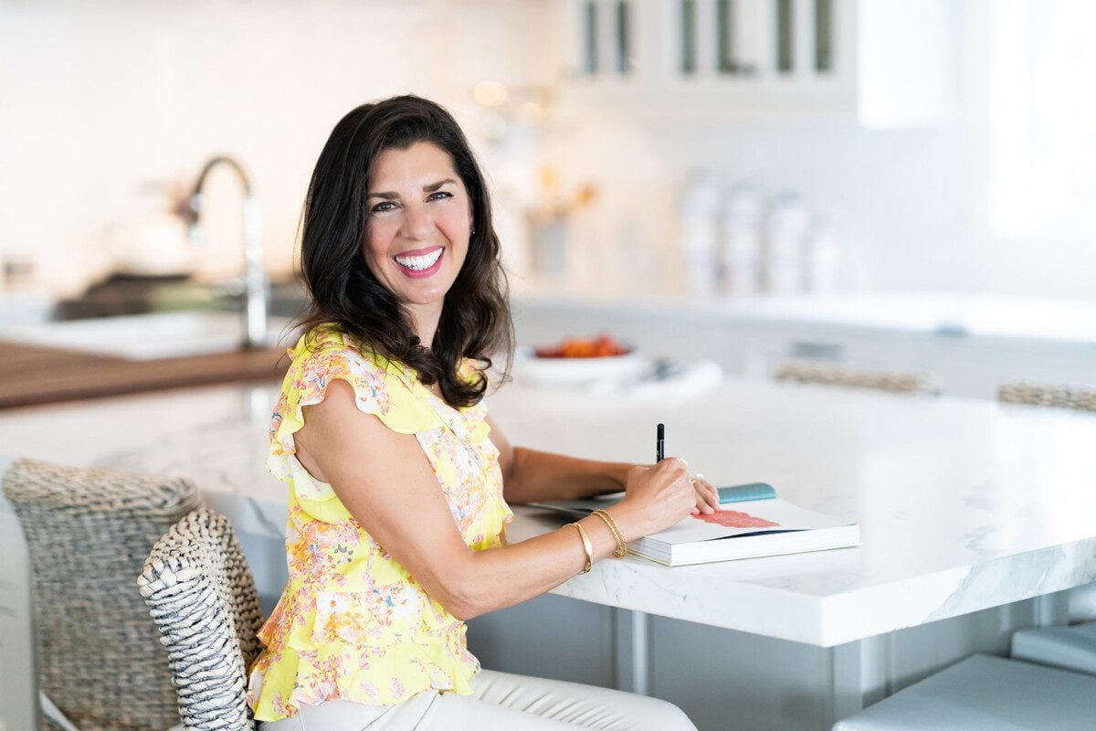 Maureen Abood signing a cookbook at the kitchen counter