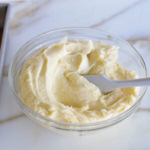 cream cheese frosting in a bowl on the counter with a spoon in it