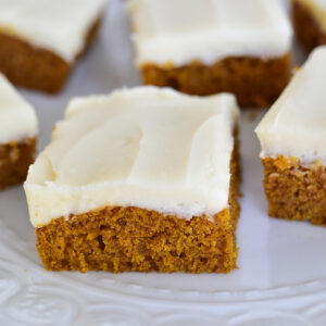 Pumpkin bars with white cream cheese frosting slices on a white plate