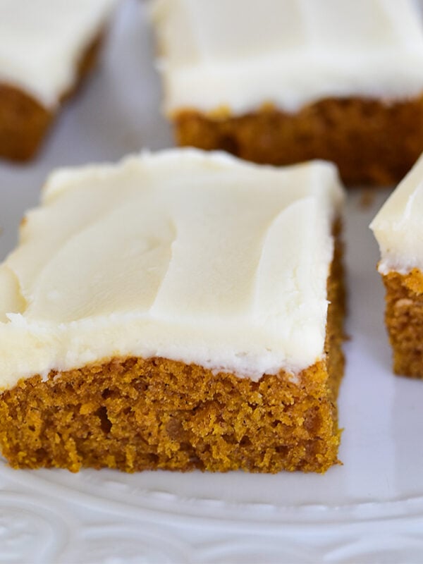 Pumpkin bars with white cream cheese frosting slices on a white plate