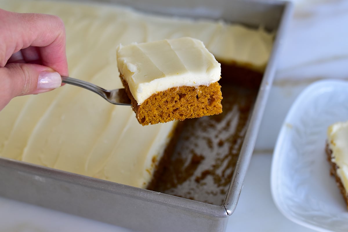 Pumpkin bar slice with white frosting on a serving spatula