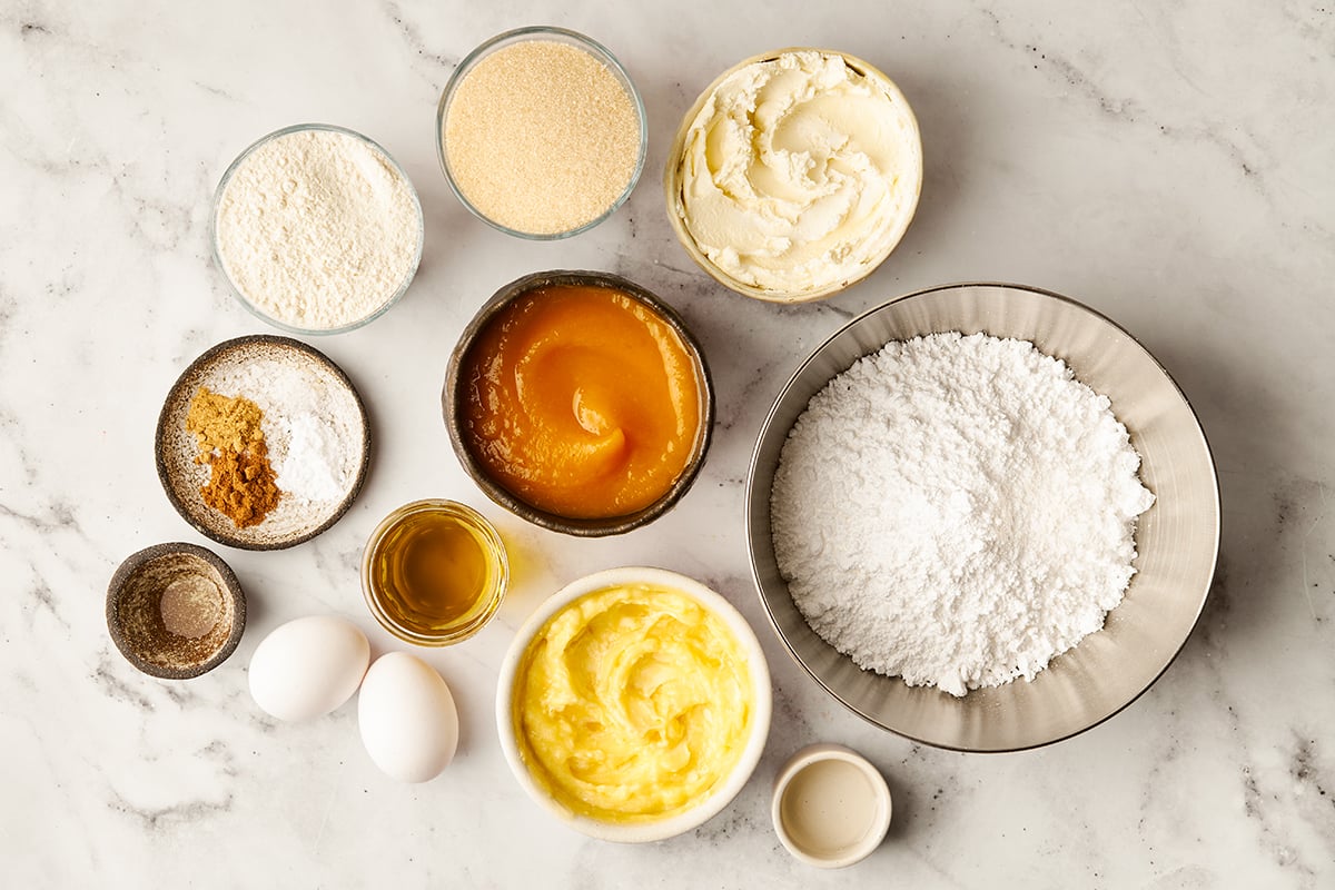 Ingredients for pumpkin bars in bowls on a marble surface