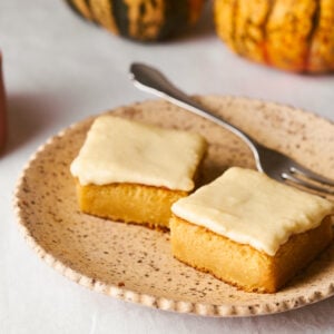 pumpkin bars on a plate with a fork and candle in the background