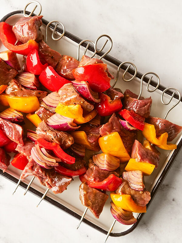 Skewers of beef shish kebab on a plate on a marble surface