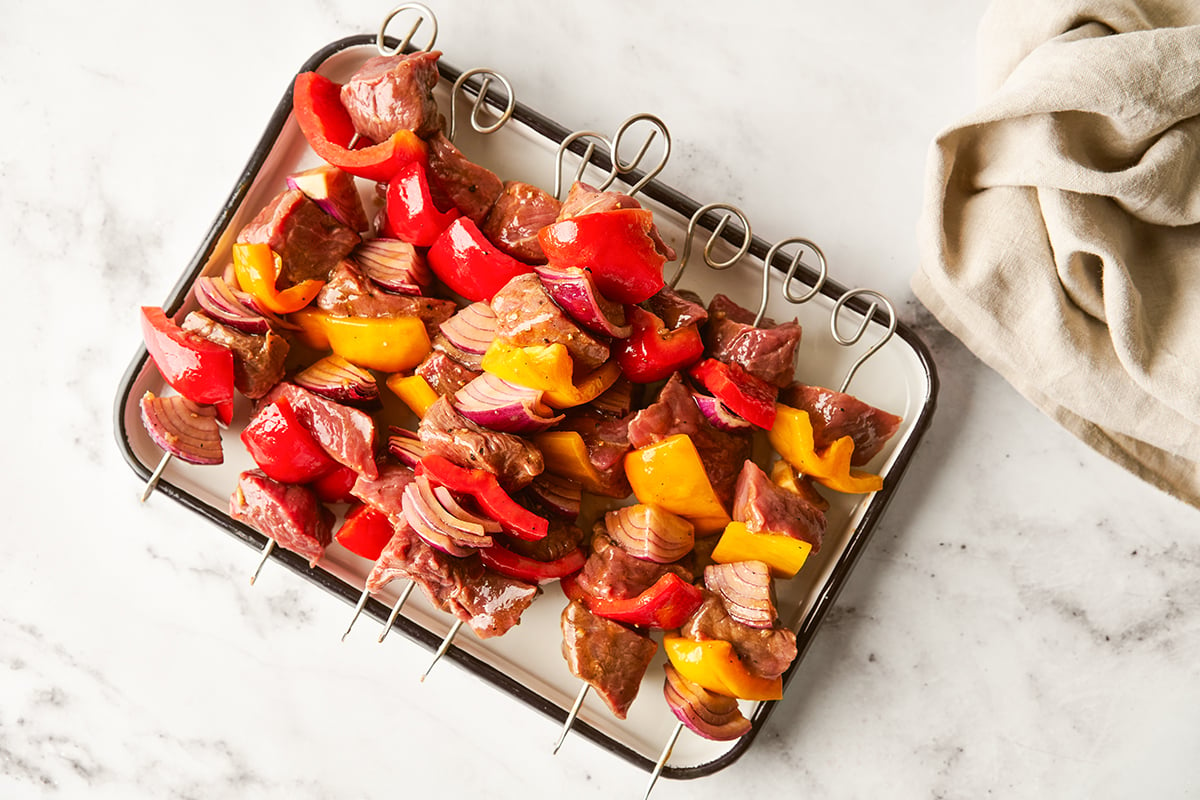 Skewers of beef shish kebab on a plate on a marble surface