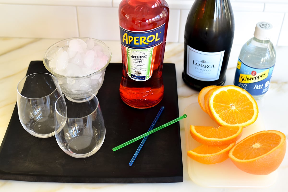 Ingredients for aperol spritz cocktail on the counter with  a sliced orange