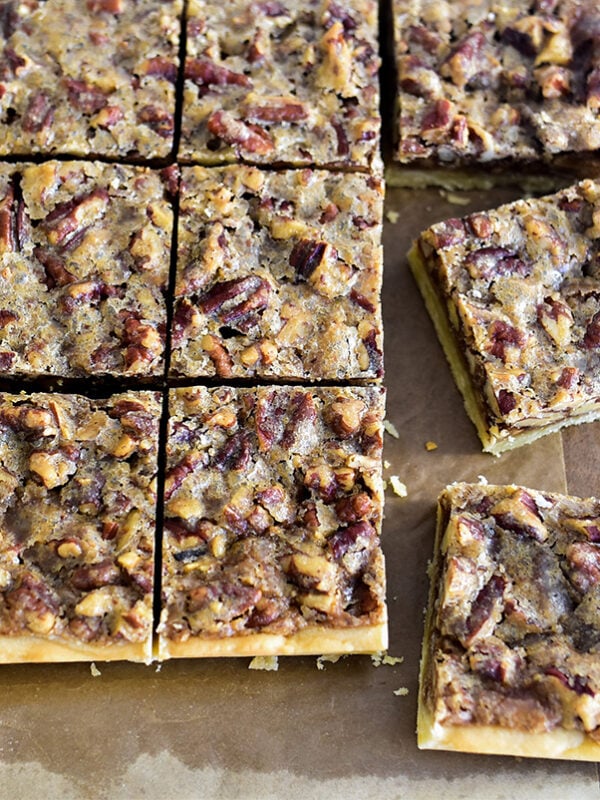 Pecan bars cut in squares with a knife beside them