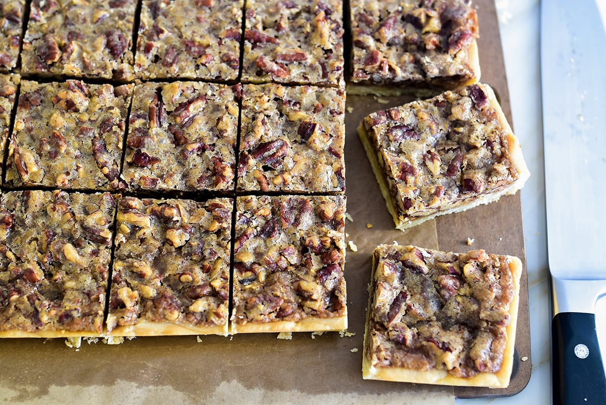 Pecan bars cut in squares with a knife beside them