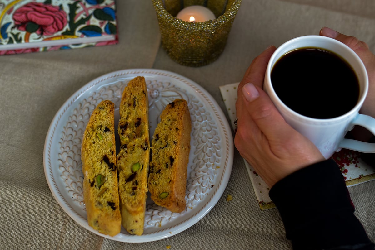 Biscotti on a plate with a cup of coffee and candle