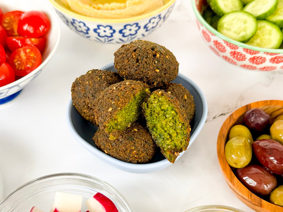 Falafel in a bowl with one cut in half with a bright green center