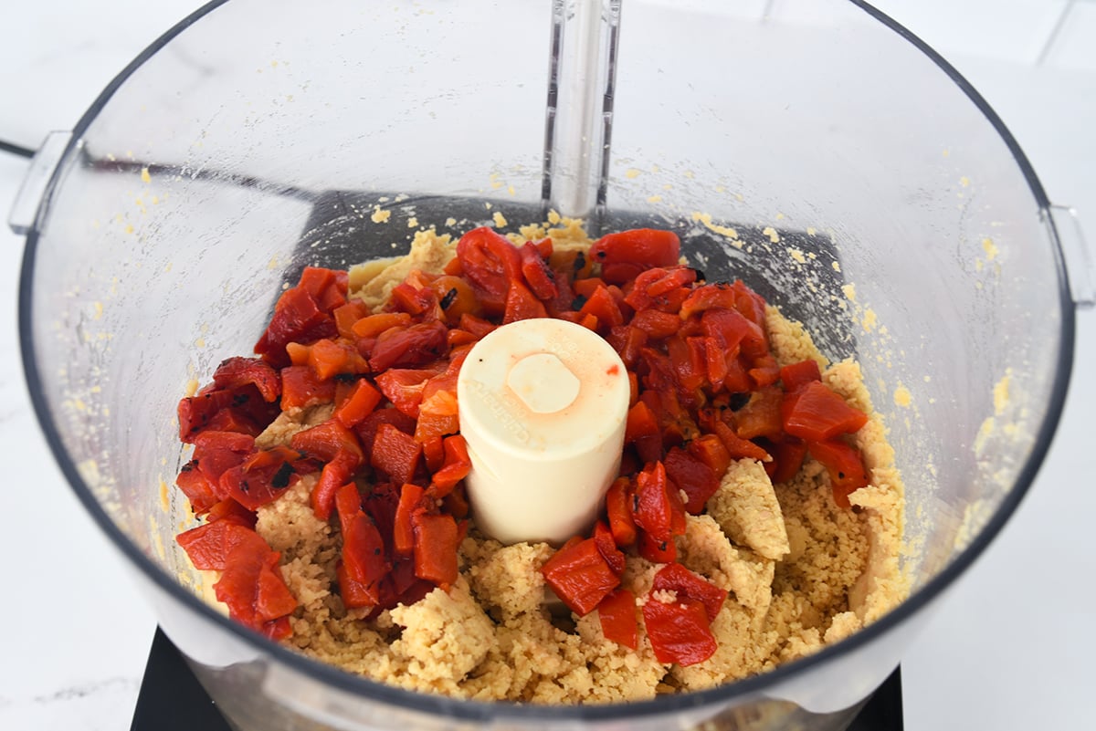 Chopped red peppers in a food processor with chickpeas