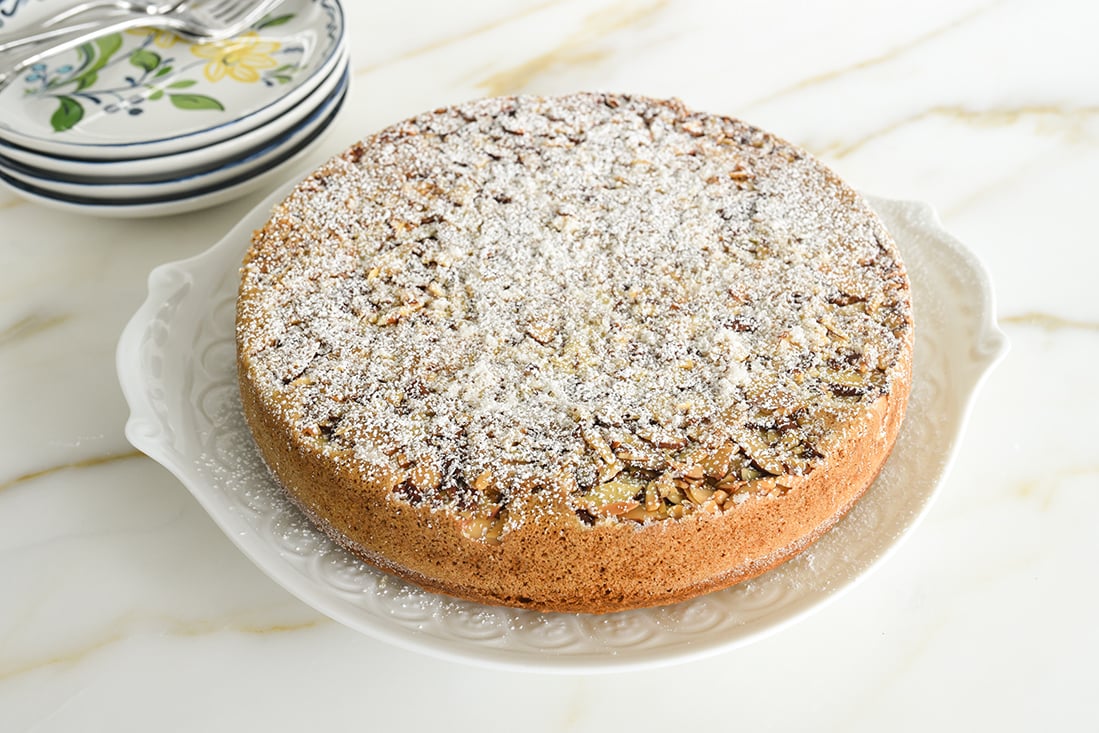 Cardamom cake with powdered sugar on top and serving plates in the background