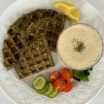 Falafel waffle on a white plate with tahini sauce