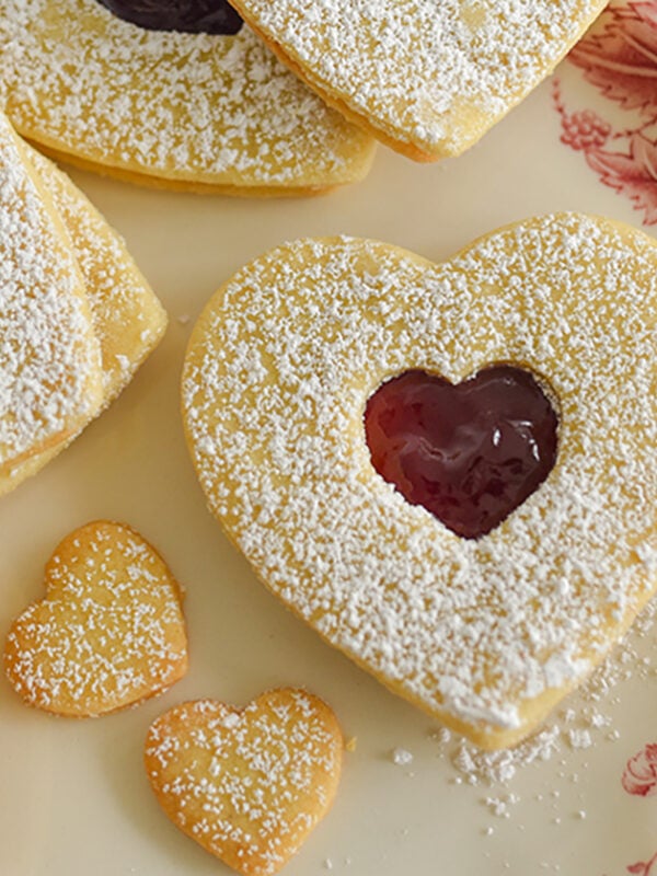 Heart cookies with a raspberry jam showing through on a pink platter