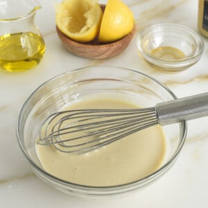 Tahini dressing in a glass bowl with a whisk