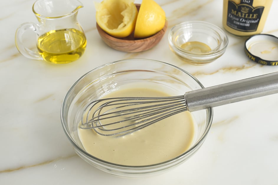 Tahini dressing in a glass bowl with a whisk