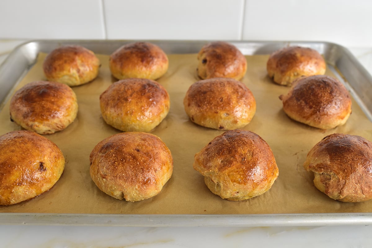 baked golden brown buns on a parchment lined baking sheet