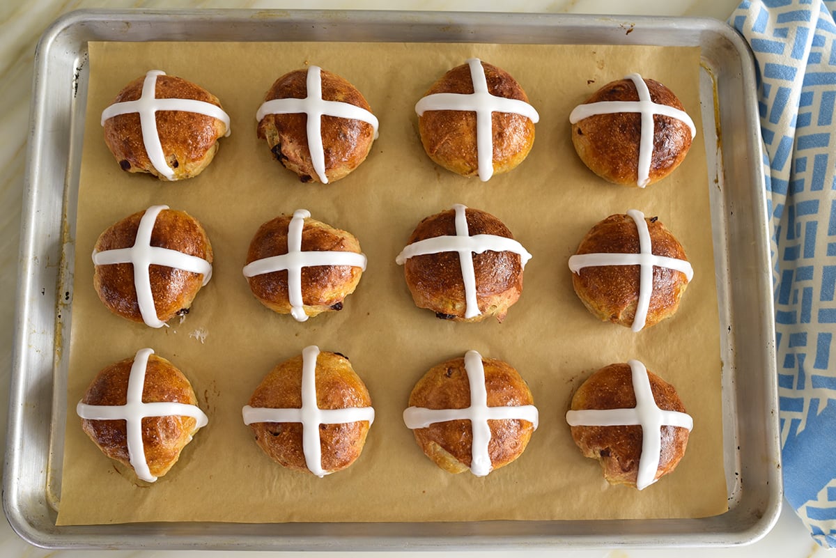 A baking sheet with 12 hot cross buns on it