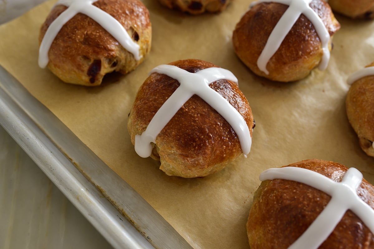 hot cross buns on a parchment lined baking sheet