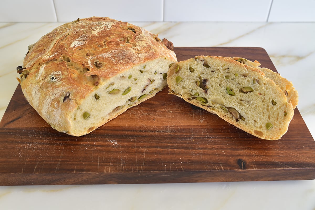 Olive bread loaf sliced on a cutting board