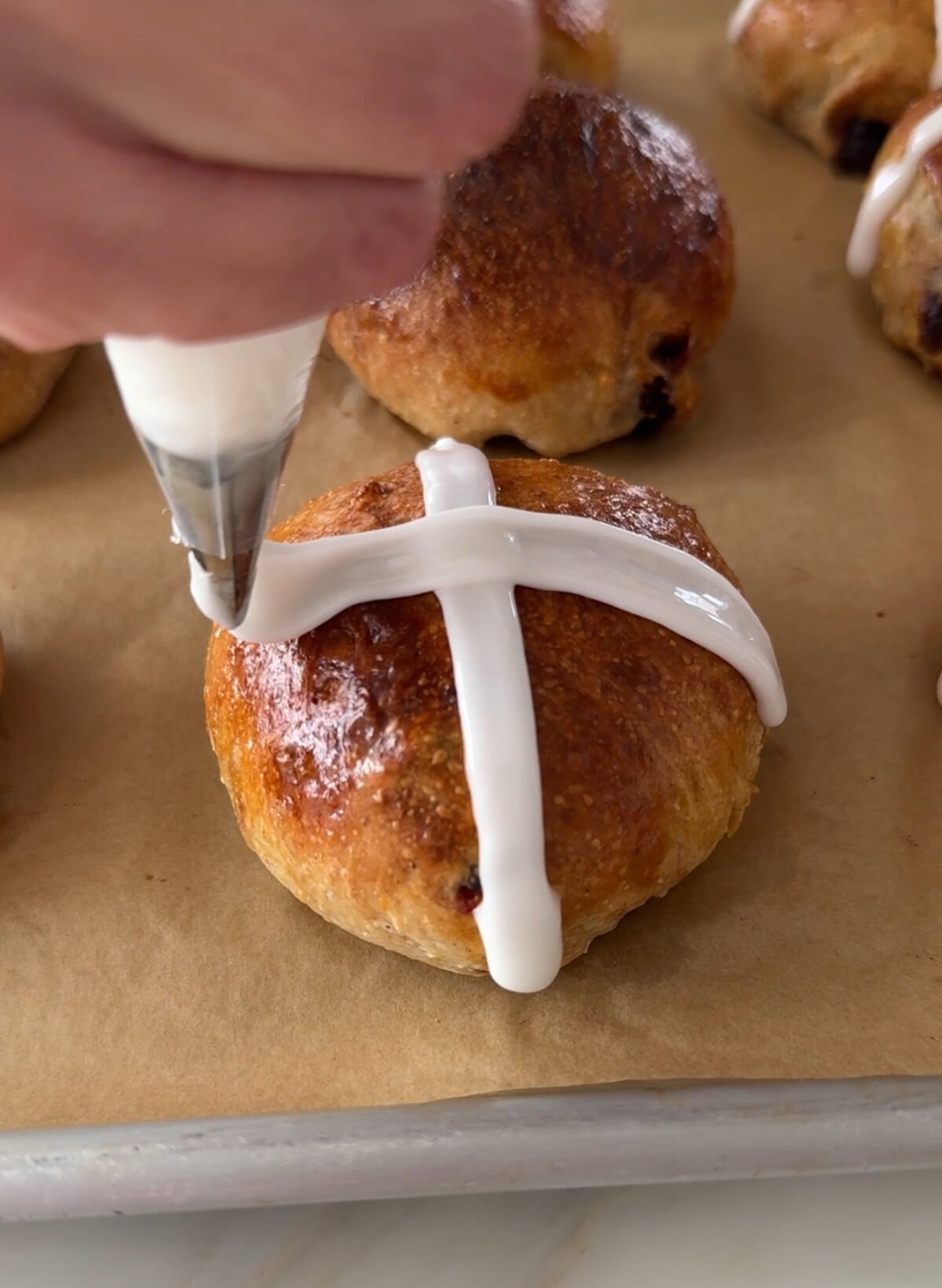 piping bag tip decorating the top of a hot cross bun