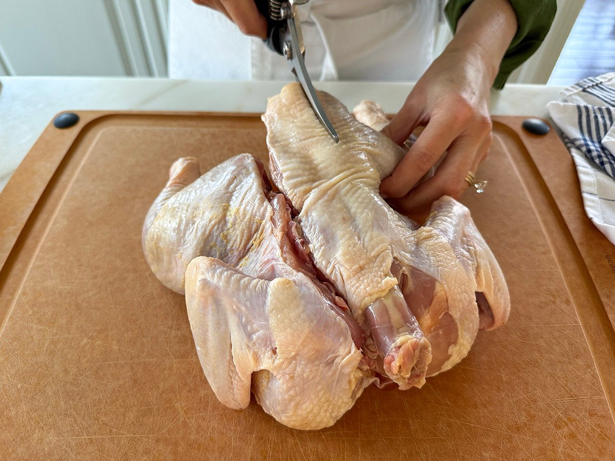 the back being cut out of a chicken with shears