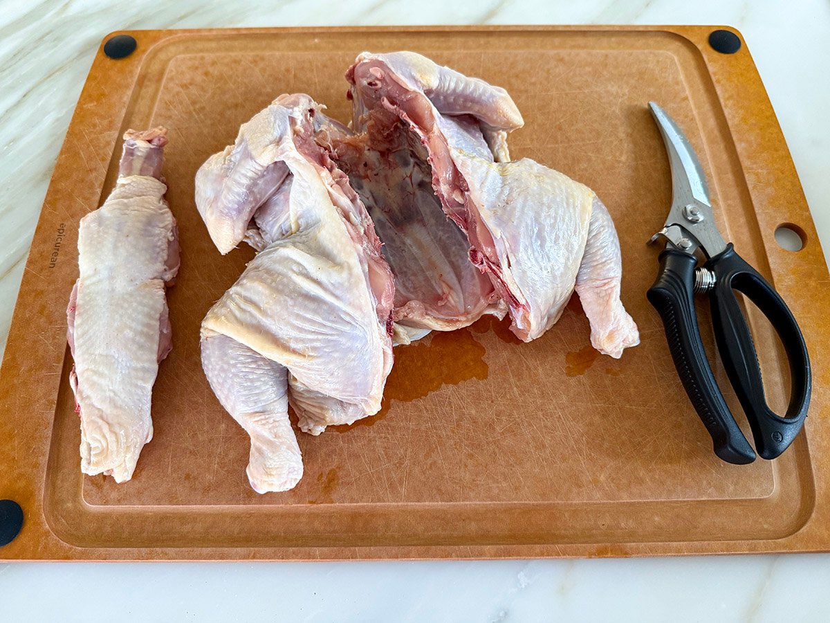 a chicken with the back cut out and the back resting next to it