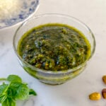 pistachio pesto in a glass dish on a marble countertop