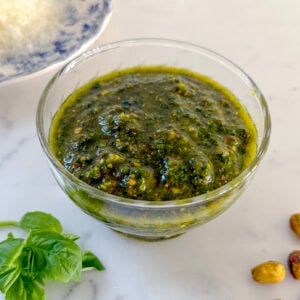 pistachio pesto in a glass dish on a marble countertop