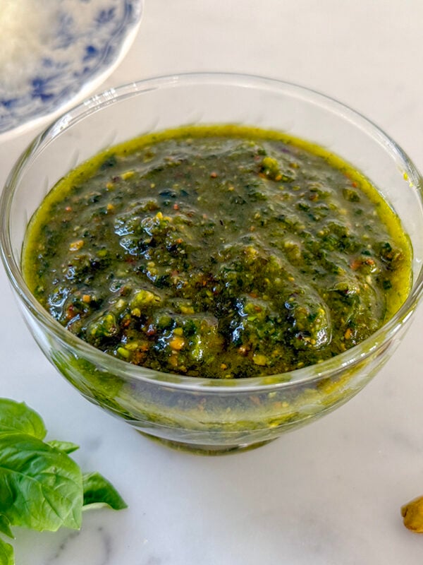 pistachio pesto in a glass dish on a marble countertop
