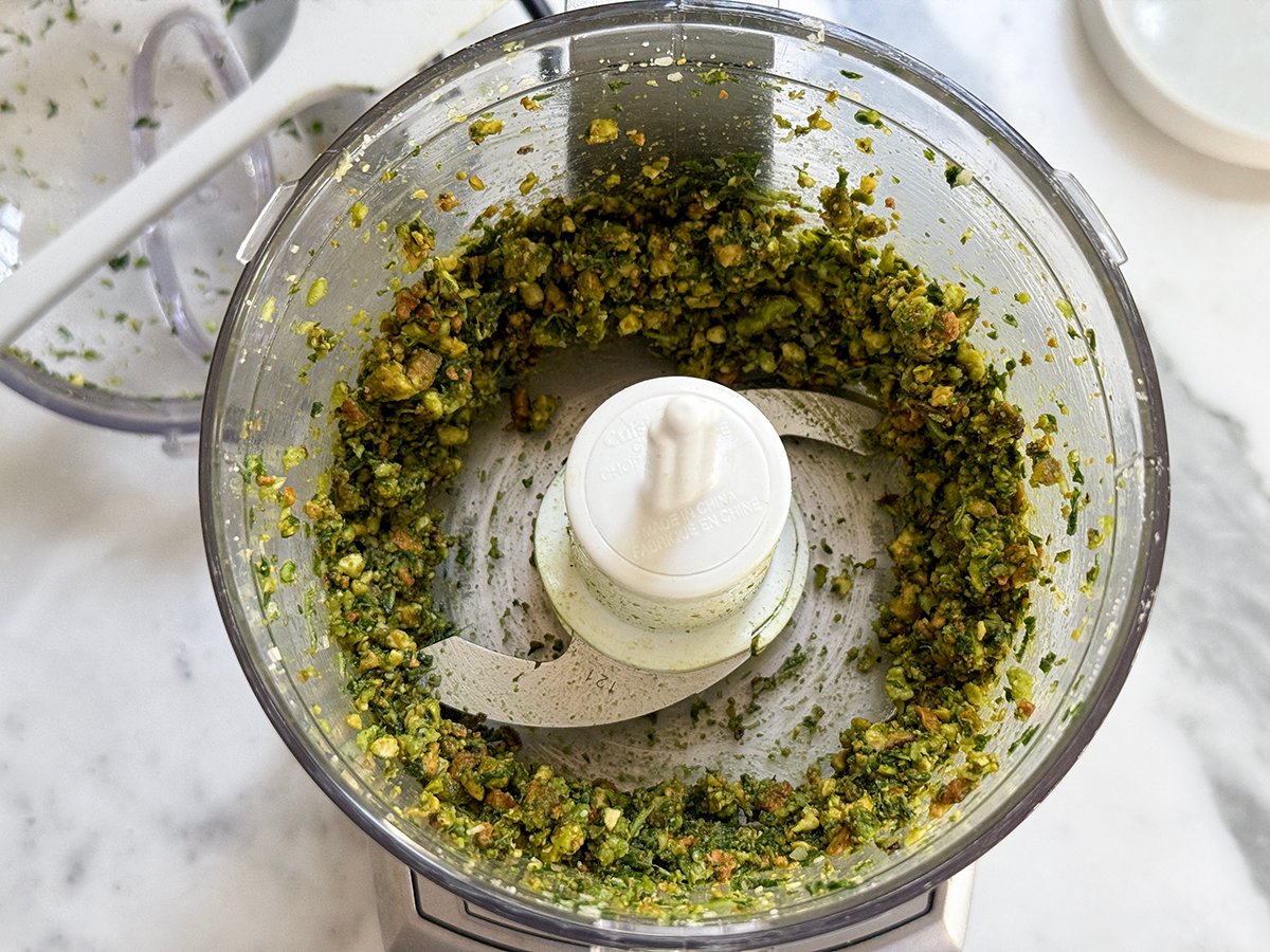 Processor with chopped pistachios and basil