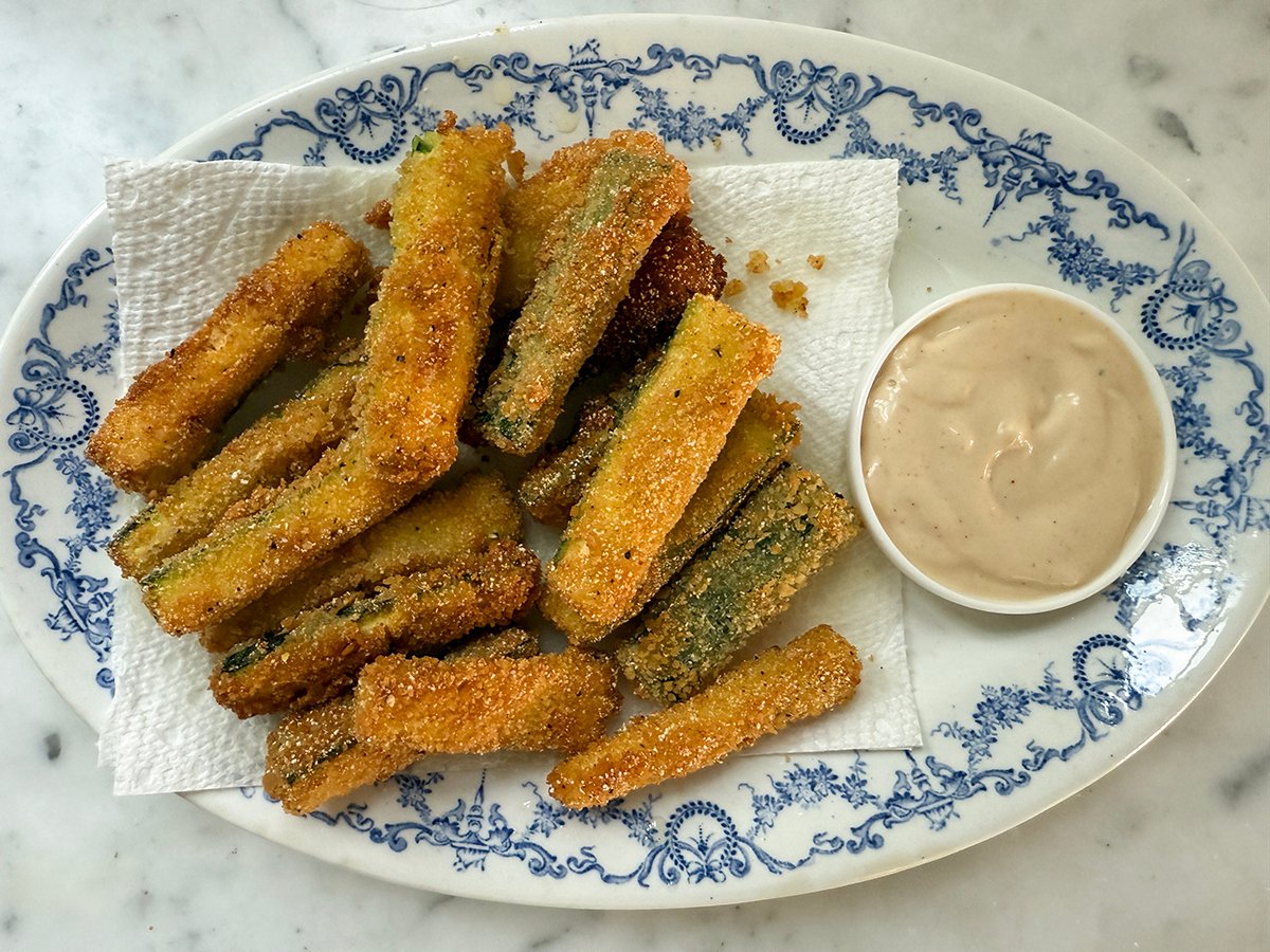 Fried Zucchini on a blue and white plate with a bowl of dipping sauce