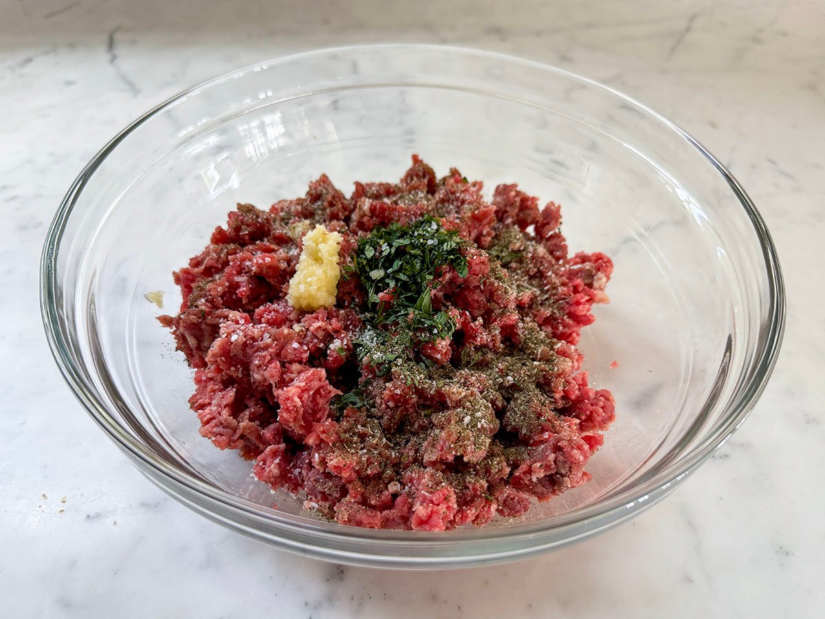 ground lamb with seasonings on top in a glass bowl