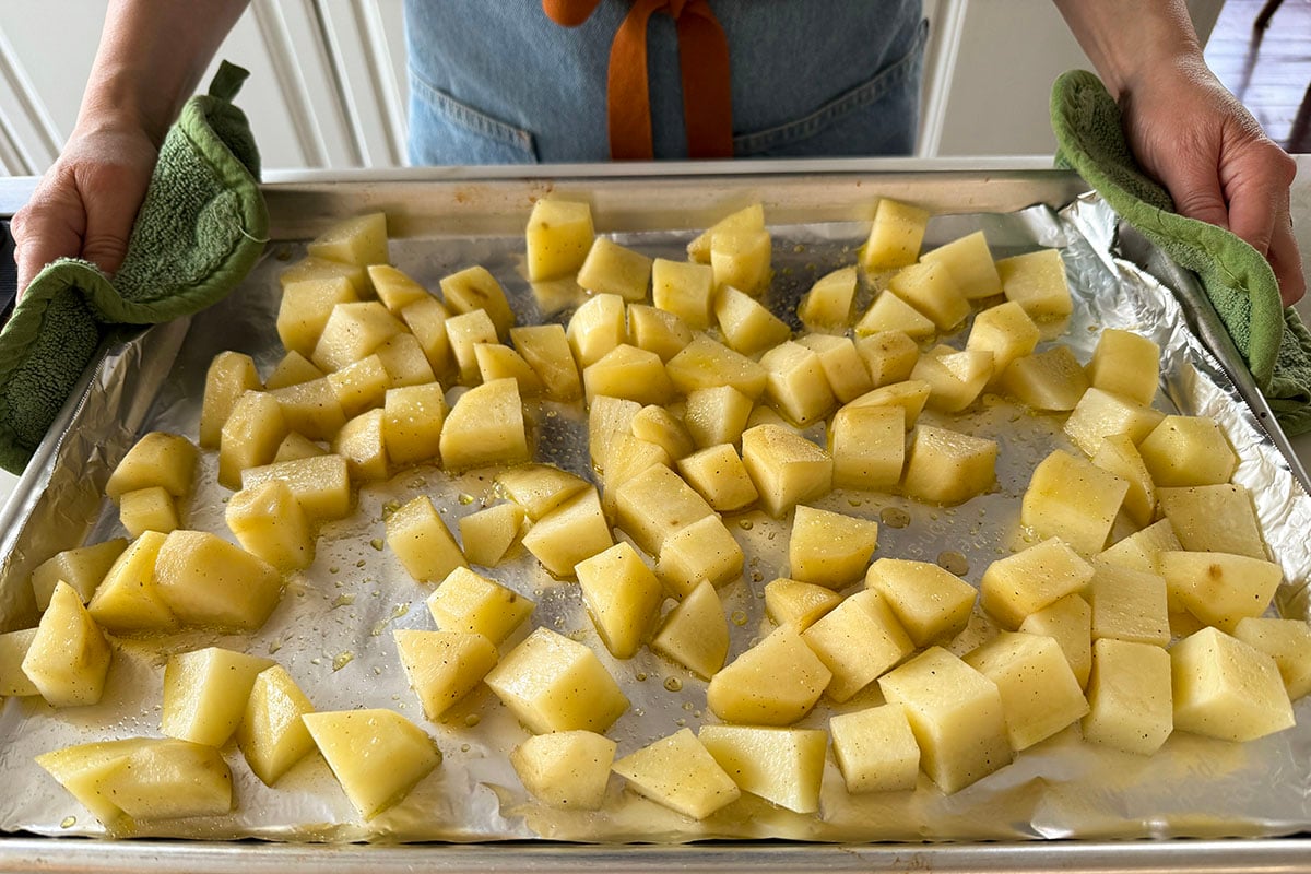 cubed raw potatoes on a baking sheet lined with foil