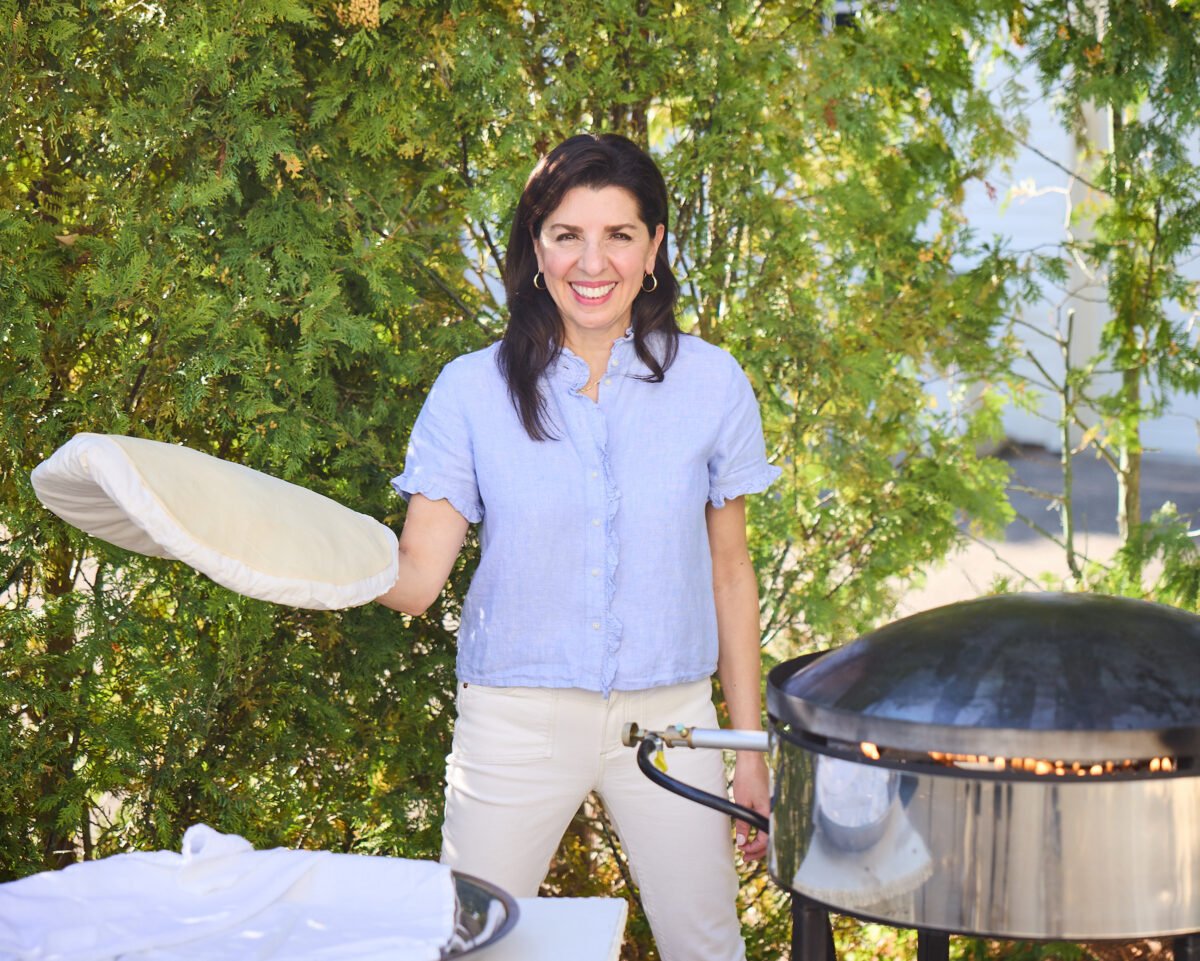 Maureen Abood standing with a saj and holding a kara pillow with dough