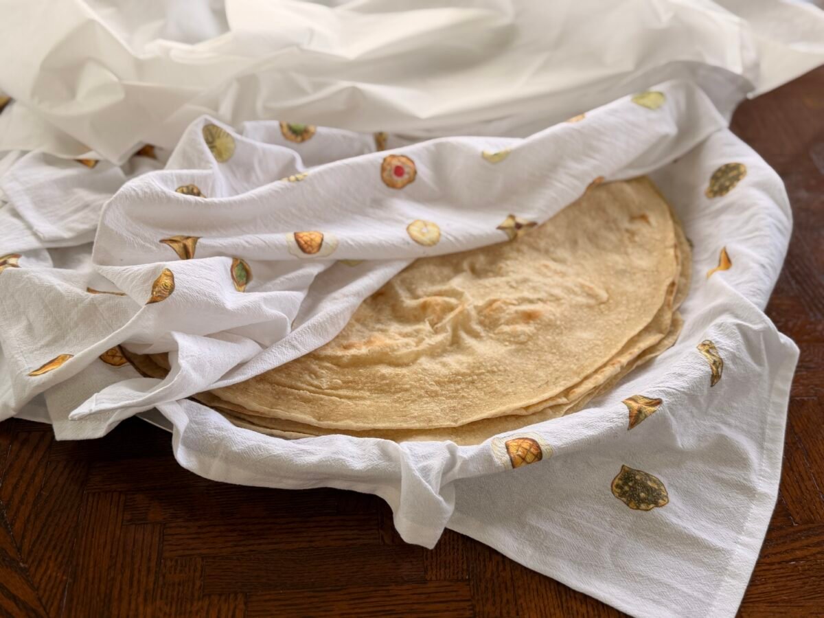 Saj bread layered with bread towels on a wood table