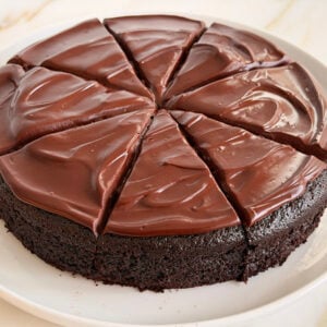 Round frosted chocolate olive oil cake cut in wedges