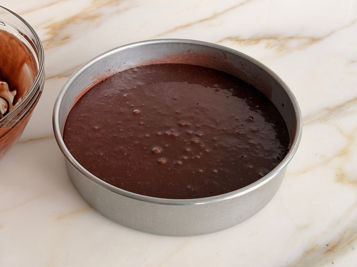 Dark chocolate cake batter in a round cake pan