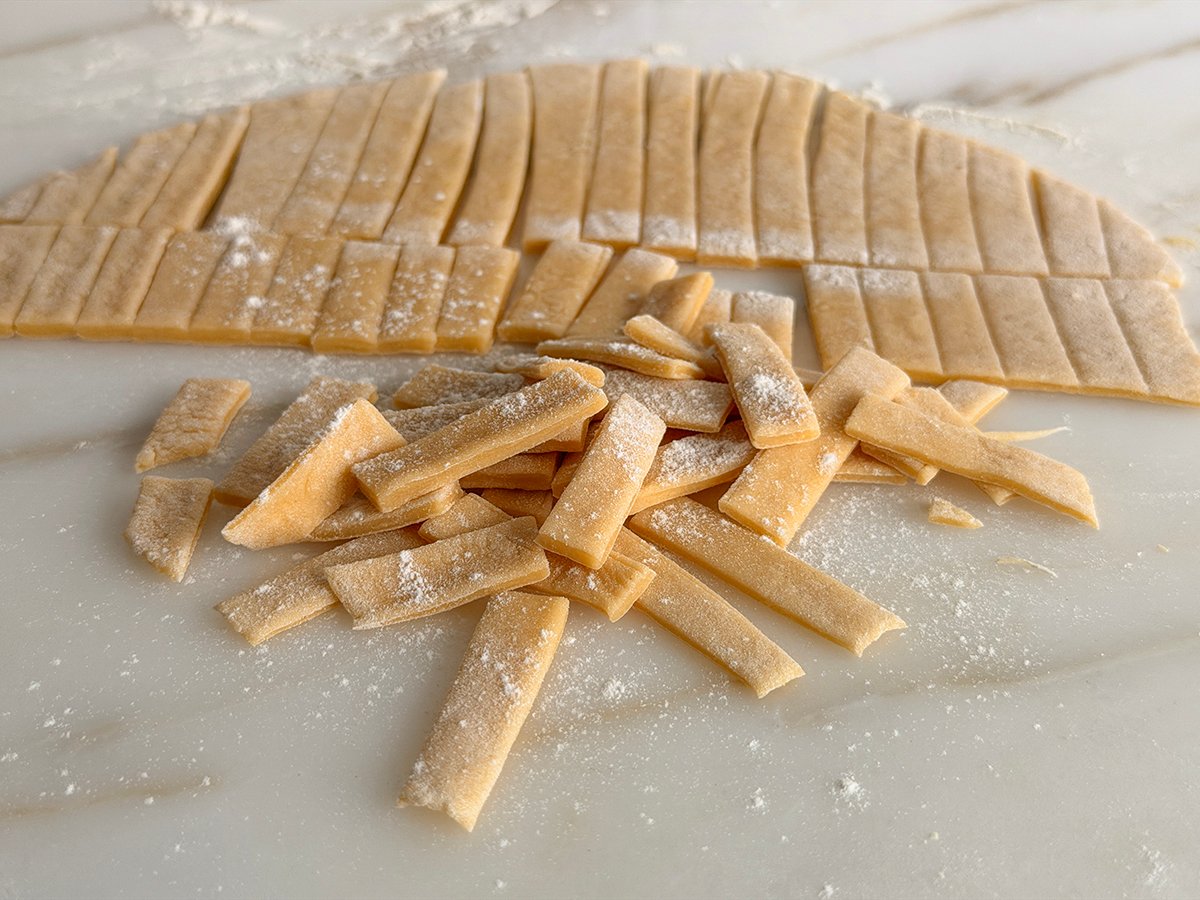 Homemade noodles tossed in flour on a marble surface
