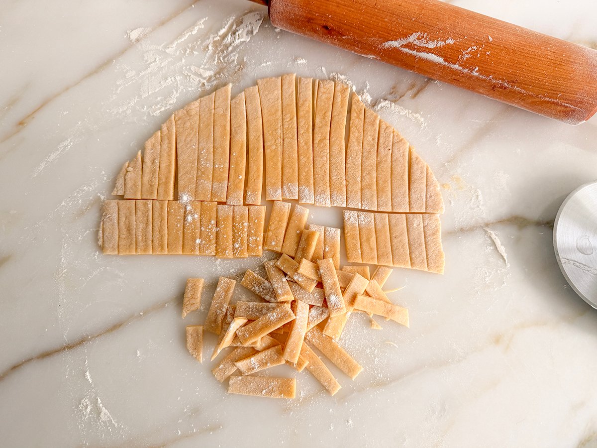 noodles cut from a rolled dough with a wood rolling pin on the side