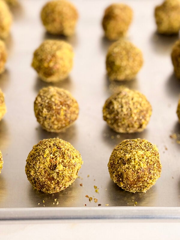 green pistachio coated energy bites on a sheet pan