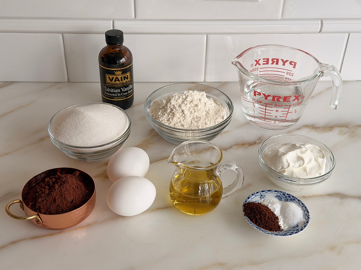 Ingredients for chocolate olive oil cake on a marble countertop
