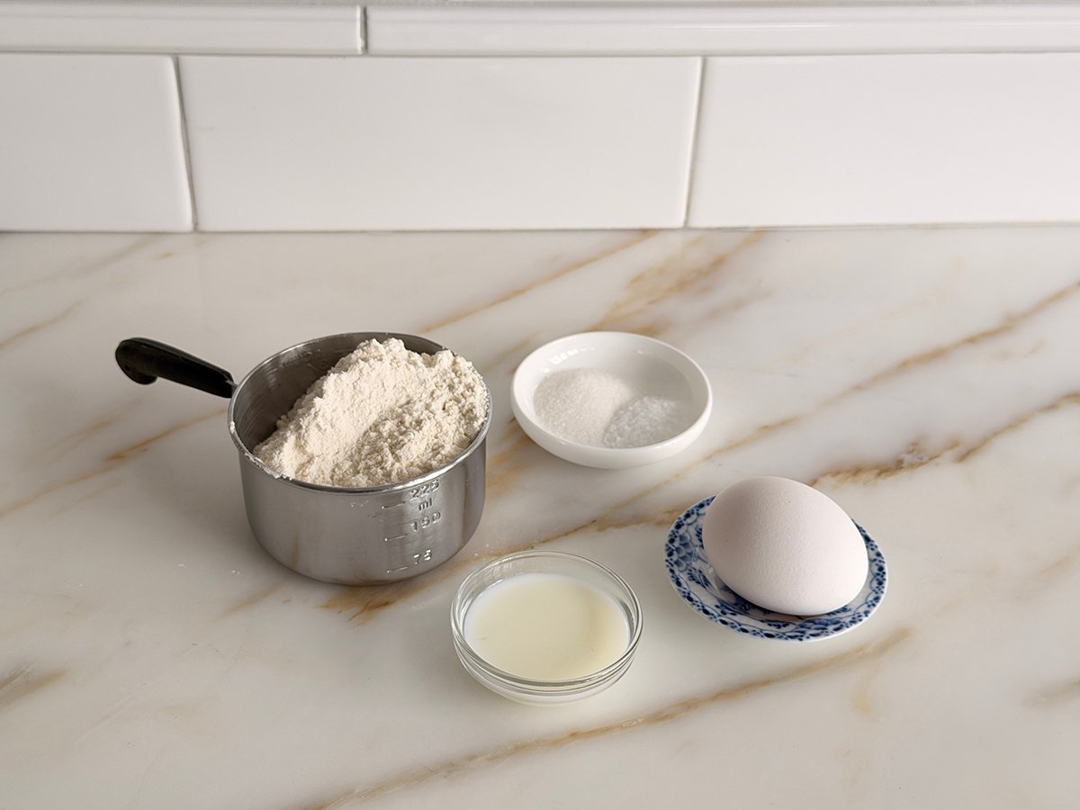 Ingredients for egg noodles on a marble counter