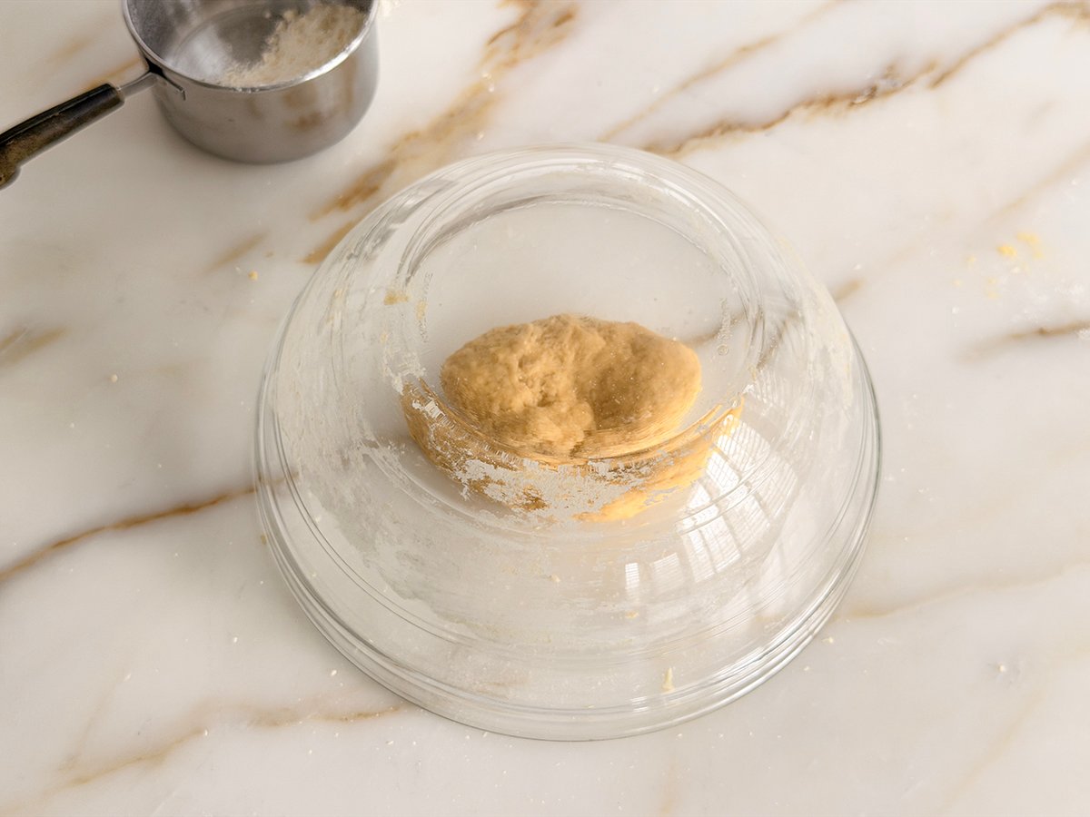 a ball of noodle dough with a glass bowl overturned over it